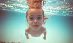 a little girl underwater wearing goggles under water