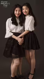 a couple of girls in short skirts posing for a photo,two girls pose for the camera while standing close together