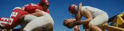 two people wearing football uniforms with helmets are standing together