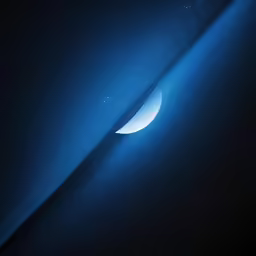 a crescent in the dark sky with stars