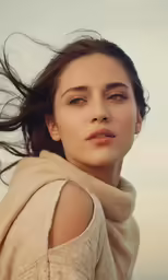 a young woman in sweater blowing her hair