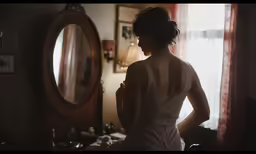 a woman in a back view standing next to a mirror