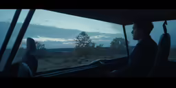 the man is looking out the car window at the mountains