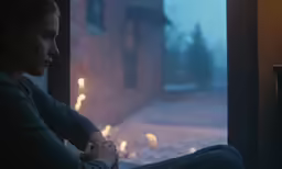 woman sitting on the window sill holding her hands together