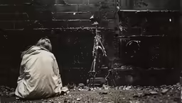 a person sitting near a wall with a lamp on it