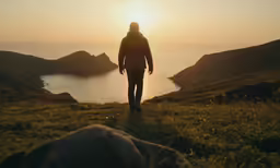 person standing on top of a grass field next to a body of water