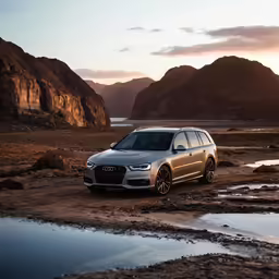 the silver suv sits at a puddle by mountains