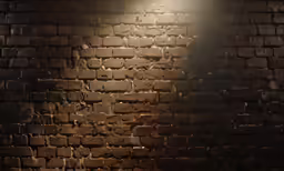 a lamp that is on and near a brick wall