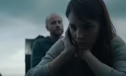 man and woman looking serious with one person covering his face