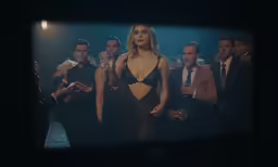 a woman is dressed in a gown and standing among the men
