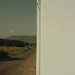 the view out of an open doorway into a dirt road