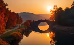 sun shining brightly over a pond with a bridge on it