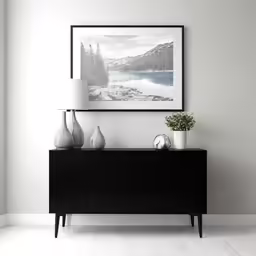 a wall with an art piece above it that is near a vase