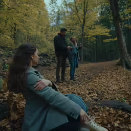 two people sitting on a dirt path in the woods