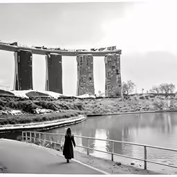 a woman is walking down the road next to a lake