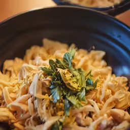 a close up shot of a dish containing noodles and greens