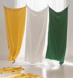 four white, green and yellow sheets hanging on a line
