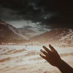 someone reaching for the sun with their hand in the snow
