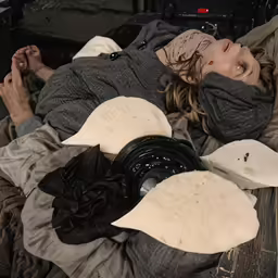 a woman with her head in a covering laying down on a bed