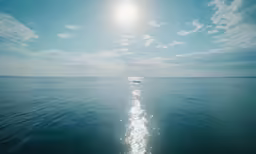 the sun shines brightly behind the wake of a boat in the ocean
