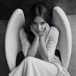 a beautiful woman laying on top of a couch with her hands clasped against the cushion