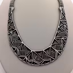 a necklace is made from metal with beads,an intricately designed necklace sits on display,an elegant, black necklace on display with bead balls and an ornate design on the front,an art nouveau necklace with a geometric design,a necklace with silver designs on it