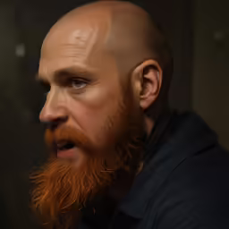 the bald head of a man is wearing a jacket and dark shirt