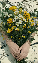 a person holding some yellow and white flowers