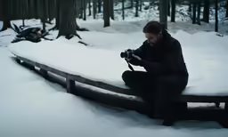 a woman in winter gear taking a photo in the woods