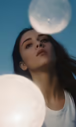 an attractive woman is looking down with the sun reflecting on her face