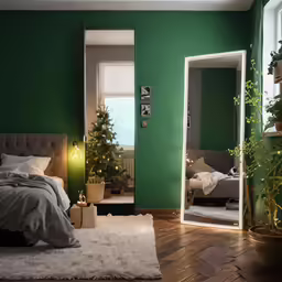 a green bedroom has a bed, desk and christmas tree