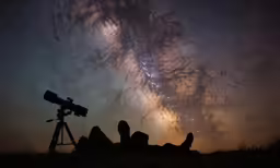 the milky and a telescope sitting on top of a field