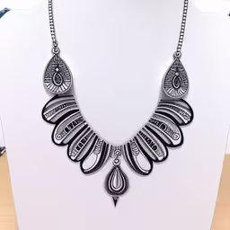 black and white necklace is on display in a stand,a necklace that is on a display stand