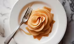 a small orange rose with a fork on a plate