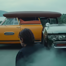 a man standing in front of an orange car