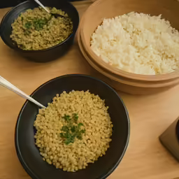 the table holds three bowls of rice and a phone