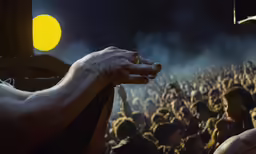 a hand holding something over a large group of people