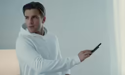 a man holding a smart phone while wearing a hoodie