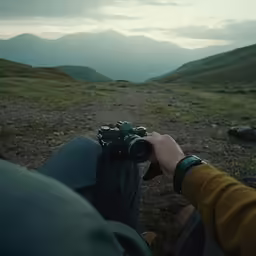 a man holding his camera up on a mountain