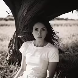 the woman is sitting under the tree under the tree