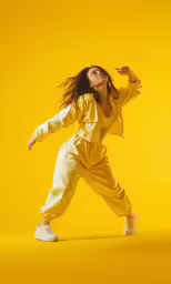 a girl poses on a yellow background in a jumpsuit