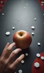 a hand is picking up a red apple