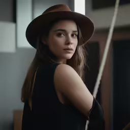 the woman is wearing a black top and brown hat