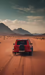 a red car on a desert road with mountains in the background