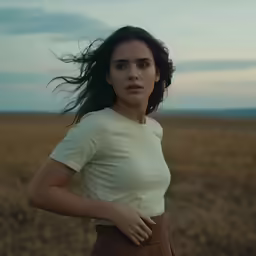 a woman with flowing hair is standing in a grassy field