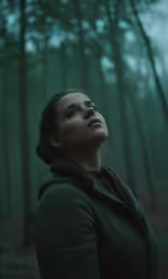 woman in the woods looking up at something