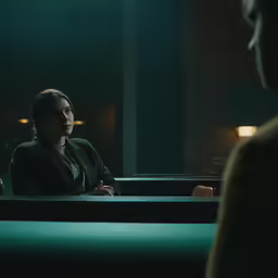the woman is sitting at the table talking with another person