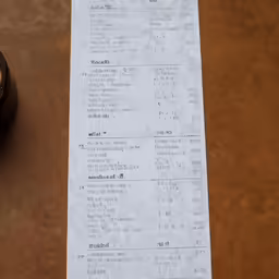 a receipt sitting on top of a brown table next to a bowl