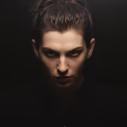 a woman is standing in the dark with her eyes closed