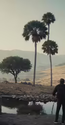 two trees and water are behind a man